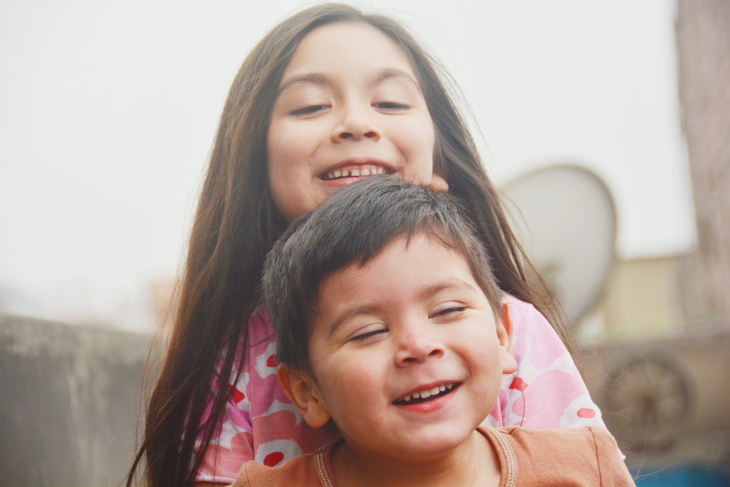 Una niña abraza a un niño pequeño mientras sonríen